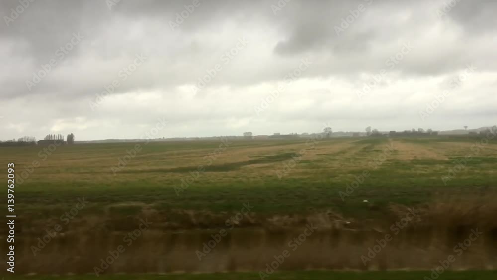 A slow motion slide view of a countryside landscape, with fields, trees and clouds, in The Netherlands
