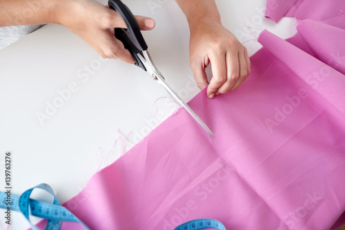 woman with tailor scissors cutting out fabric