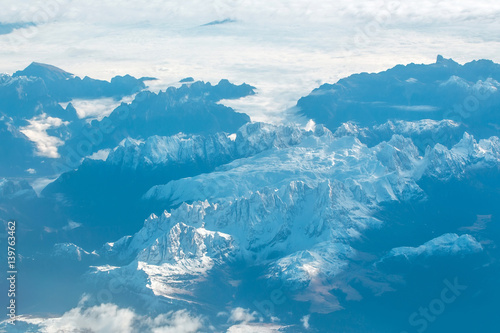 Idyllic snowy mountain peaks under clouds from plane