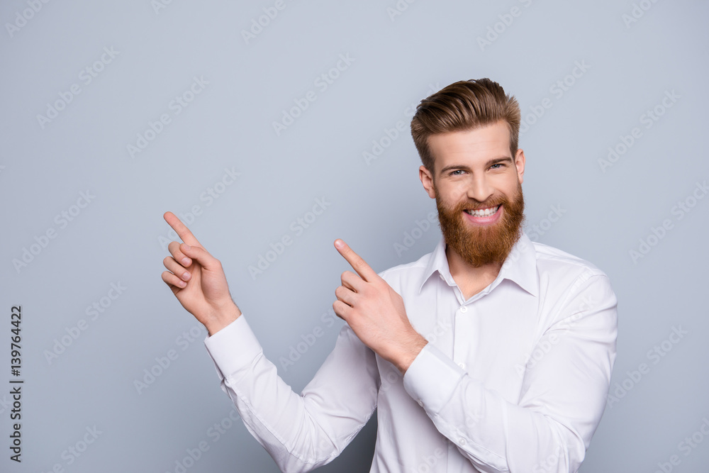 Portrait of serious confident bearded man pointing with fingers on copy space and smile Portrait of serious confident bearded man pointing with fingers on copy space and smile