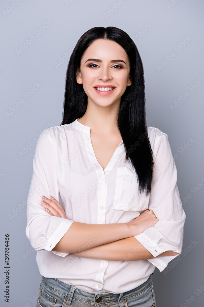 Portrait of beautiful cheerful young woman keeping crossed hands, smiling and looking at camera Portrait of beautiful cheerful young woman keeping crossed hands, smiling and looking at camera