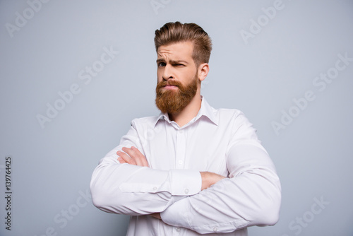Portrait of serious confident bearded man keeping  crossed hands and expressing distrust emotion photo