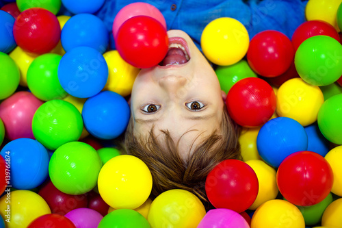 Happy boy playing in colorful balls. Happy child playing at colorful plastic balls playground high view photo