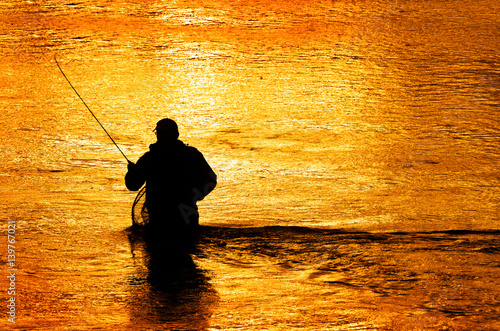 Silhouette of Man Flyfishing in River photo