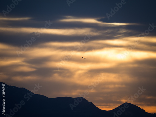 plane descending over mountains at sunset