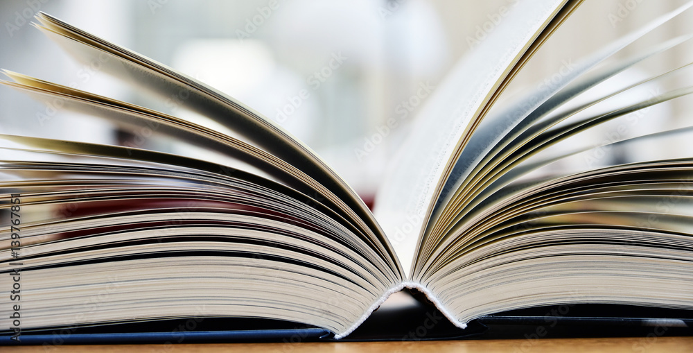 Fototapeta premium Książka w twardej oprawie leżąca na stole w bibliotece