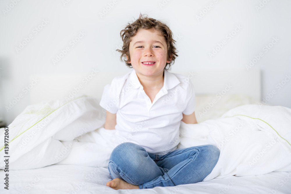 Adorable little boy in white t-shit lying in bed Adorable little boy in white t-shit lying in bed