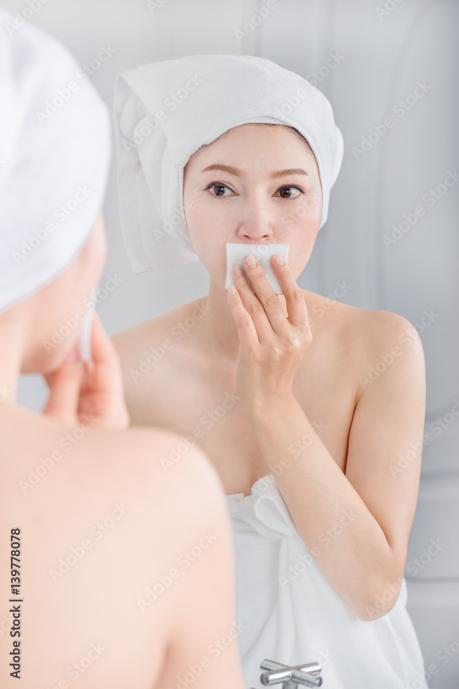 woman looking mirror and cleaning her face with cotton woman looking mirror and cleaning her face with cotton