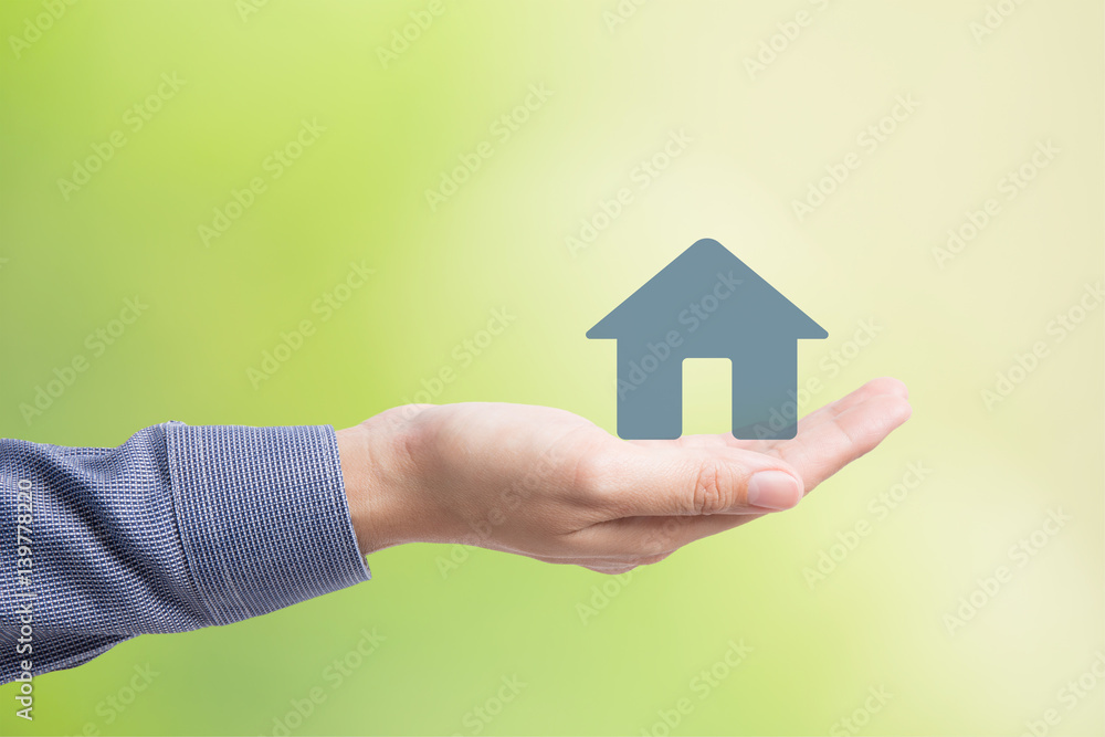 Naklejka premium Male hand holding house on green background
