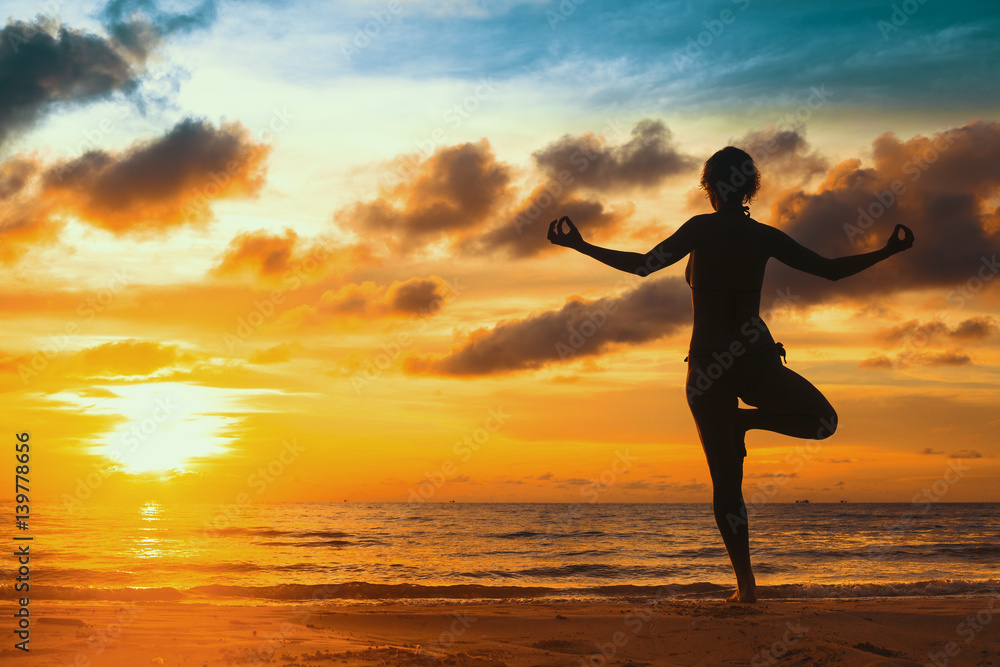 Silhouette young woman practicing yoga on the beach at sunset. Silhouette young woman practicing yoga on the beach at sunset.