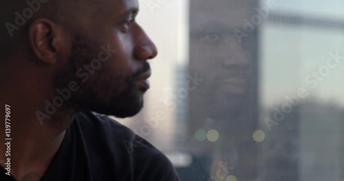 Handsome African American man looks past his reflection in window overlooking the Downtown Los Angeles skyline.  Big close up, recorded in slow motion at 60fps.