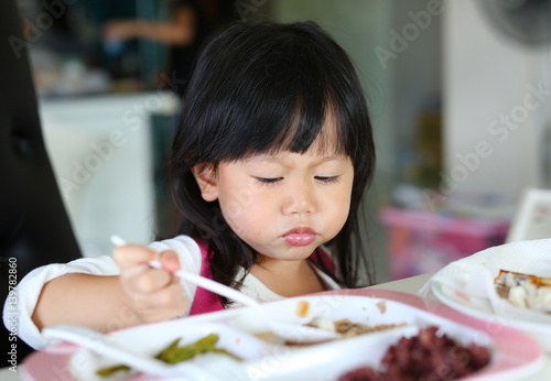 Close-up asian kid girl age about 2 years old eating rice by self