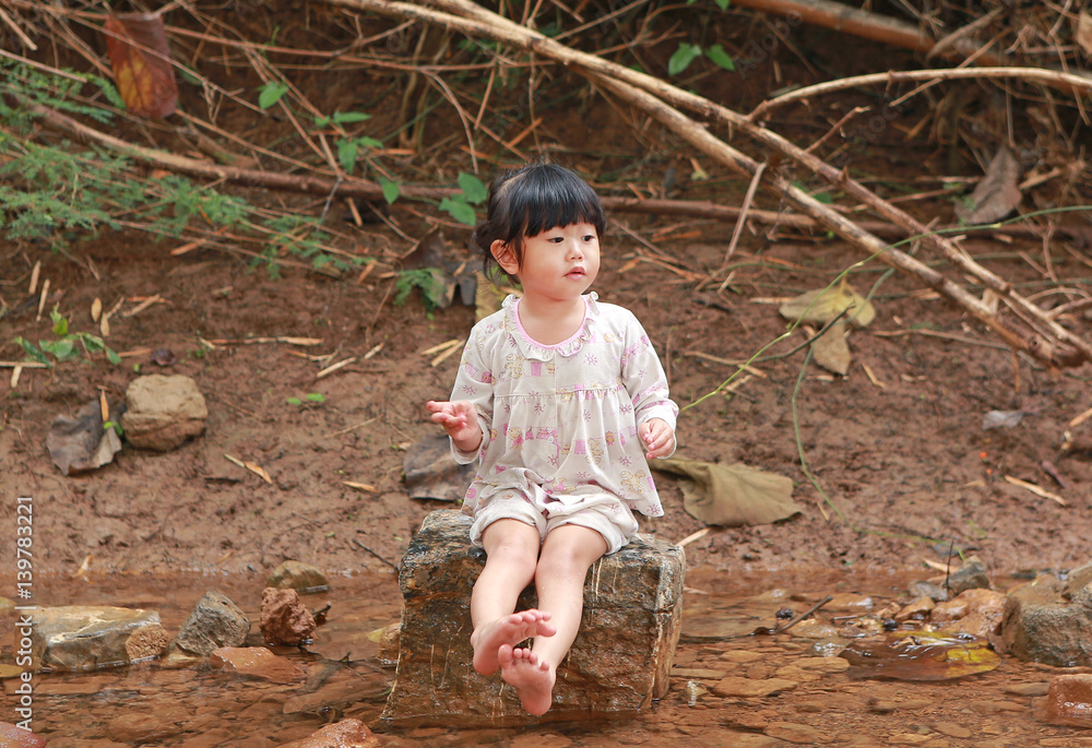 Little child girl sitting on stone and playing water, countryside thailand. Little child girl sitting on stone and playing water, countryside thailand.