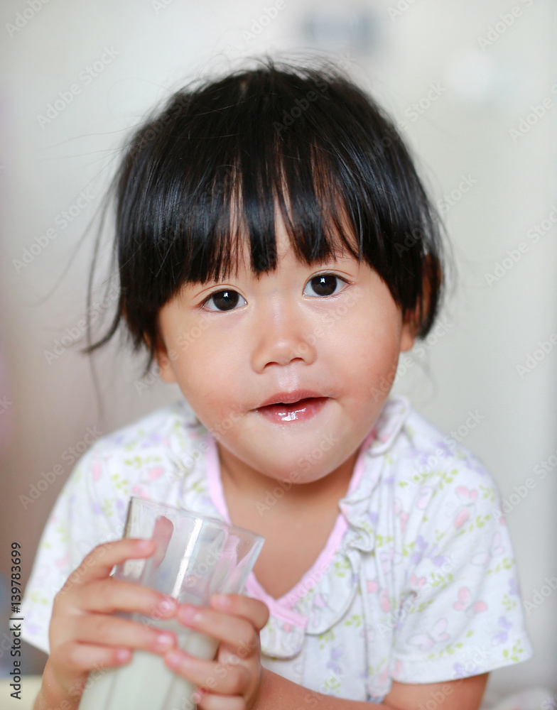 Close up of little girl in pajamas drinking milk from glass indoor at the morning. Close up of little girl in pajamas drinking milk from glass indoor at the morning.