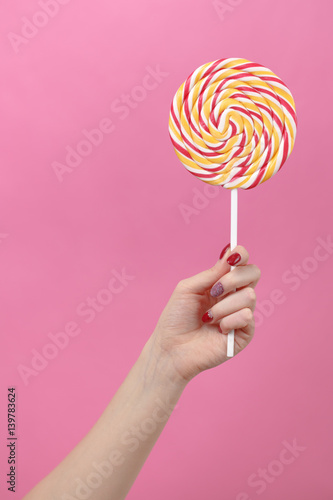 Female hand hold lolipop on pink background