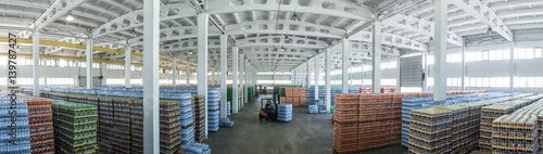 panoramic view of a large warehouse with drinks in plastic bottles with loading machines