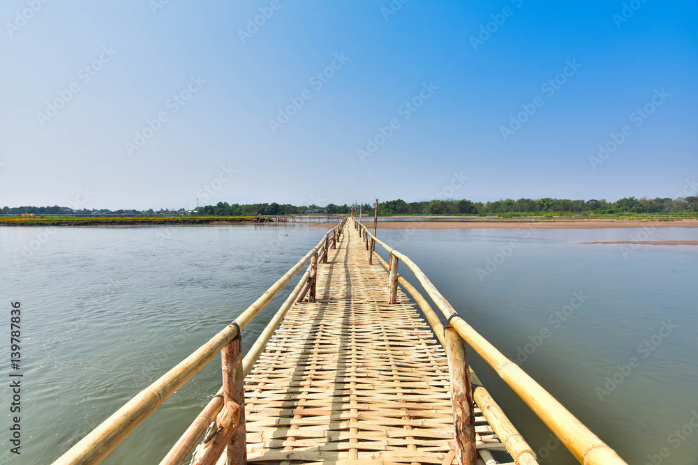 beautiful long bamboo bridge on river with blue sky at sunny day. soft focus