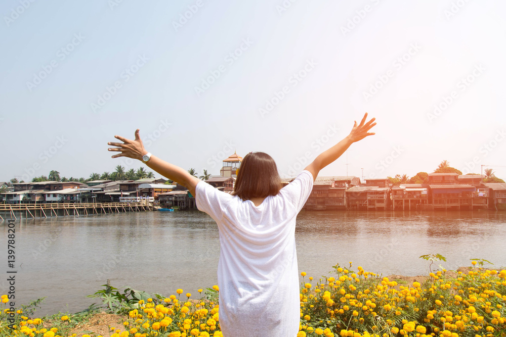 happy woman stand with marigold flower with river view at sunny day. subject is soft focus happy woman stand with marigold flower with river view at sunny day. subject is soft focus