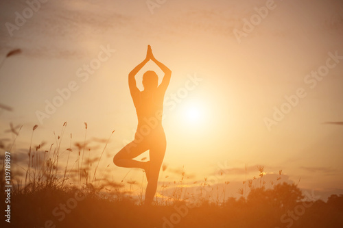 Silhouette of woman praying over beautiful sky background