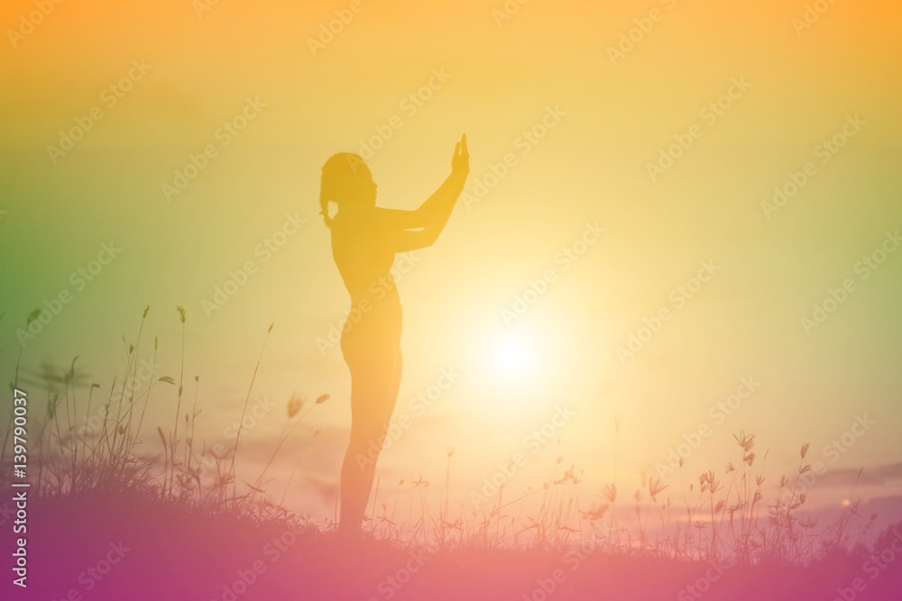 Silhouette of woman praying over beautiful sky background