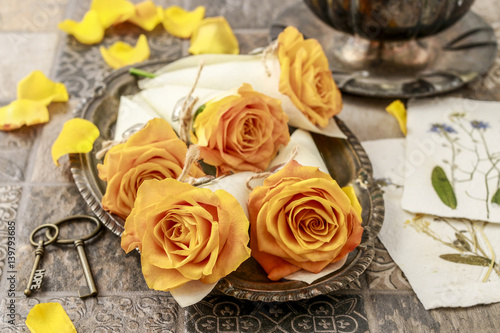 Orange roses in paper wrapping decorated with silver hearts.