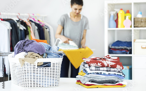 Photography Young woman ironing clothes on ironing board