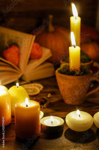 Autumn decorations: candles on wooden table in the evening.