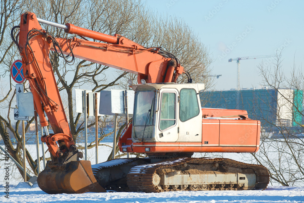 Caterpillar white-orange excavator close up in the sunny February day Caterpillar white-orange excavator close up in the sunny February day