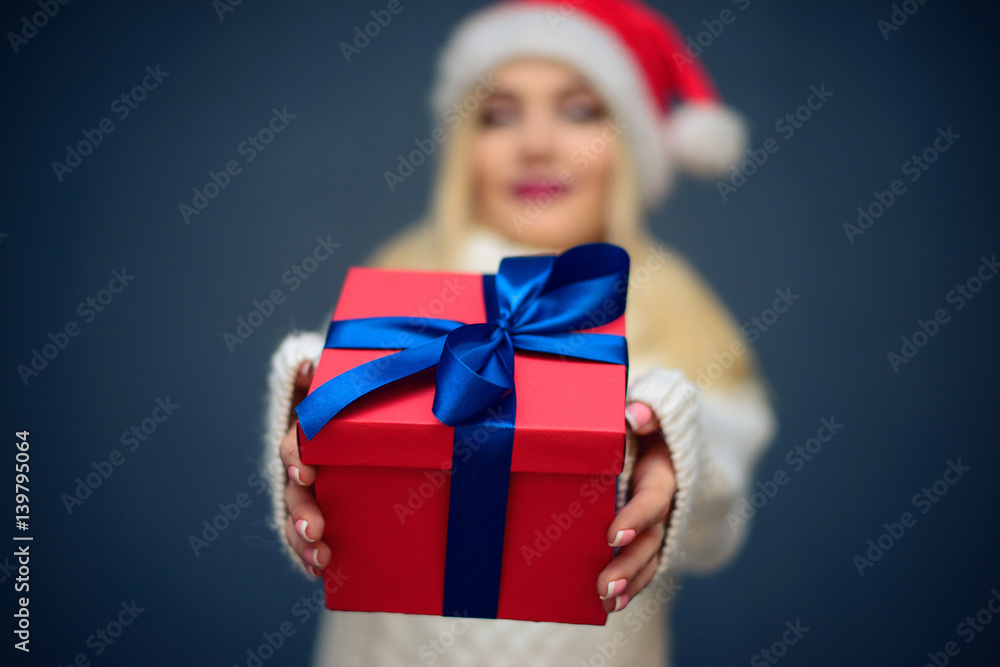 Portrait of a beautiful woman wearing a santa hat holding christmas gift box Portrait of a beautiful woman wearing a santa hat holding christmas gift box