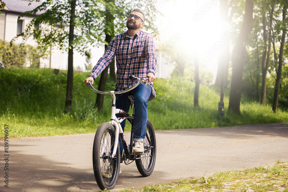 Fototapeta premium Young modern man riding bike in park thinking