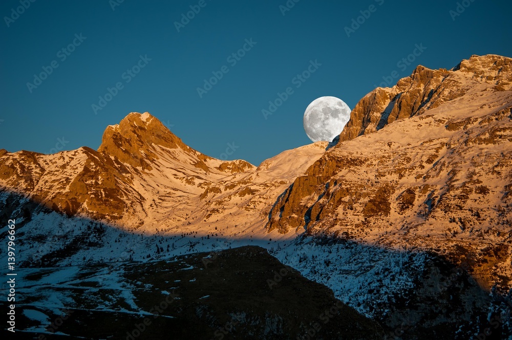 snowy mountain at sunset with full moon
