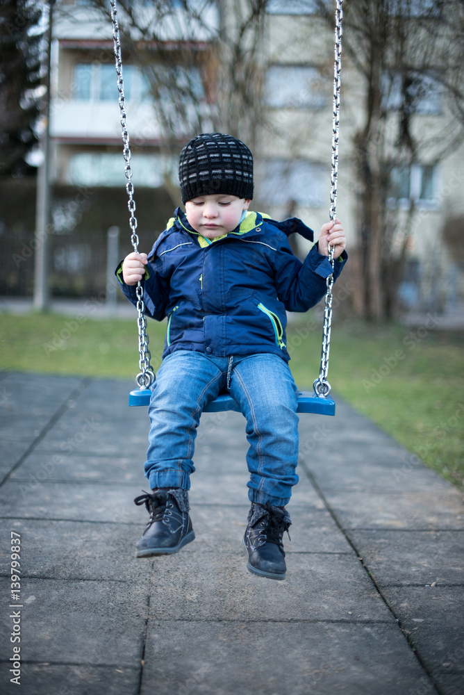 Little boy swinging on swing at children playground Little boy swinging on swing at children playground