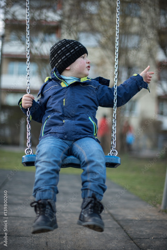 Little boy swinging on swing at children playground Little boy swinging on swing at children playground