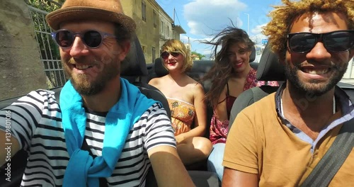 Four young people enjoying their road trip in convertible car