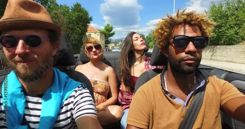 Four young people enjoying their road trip in convertible car