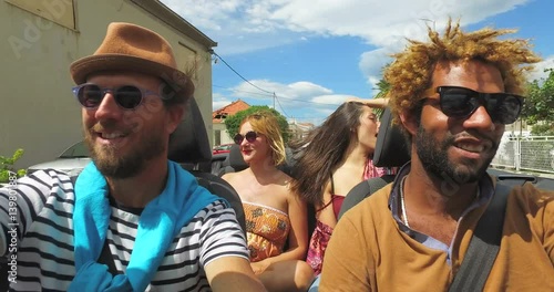 Four young people enjoying their road trip in convertible car