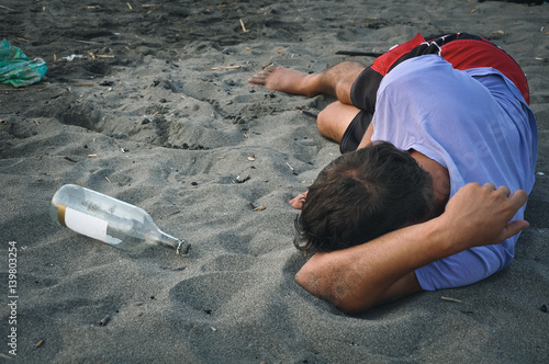 Drunk man sleeping on the sand at the beach