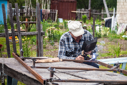 Elderly man welding metal construction