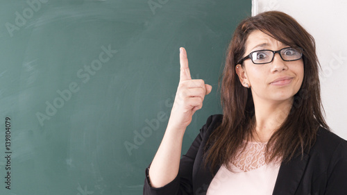 Junge Frau zeigt mit dem Finger auf eine Tafel.