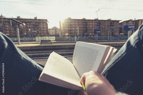 Reading a book while waiting for the train. Pov. Commuters lifestyle