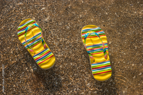Flip flops on the shore. Transparent water with sand. Summer holidays at tropical island. Voyage to the sea.