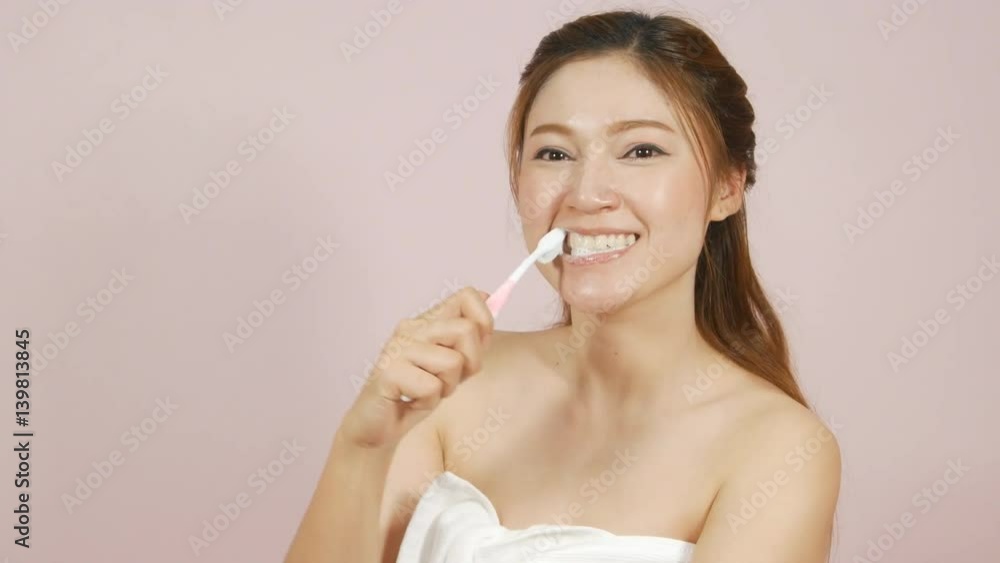 4k of happy beautiful woman brushing her teeth on pink background 4k of happy beautiful woman brushing her teeth on pink background