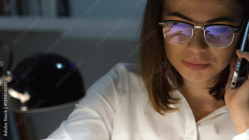 Smiling happy business woman talking on mobile phone while workig with documents in office Smiling happy business woman talking on mobile phone while workig with documents in office