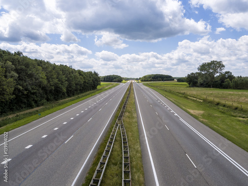 four lane motorway with no traffic except in the far distance, on a sunny day © hoeks