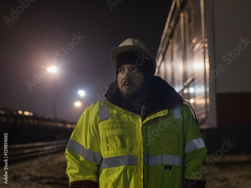Portrait of young warehouse worker in helmet at night.