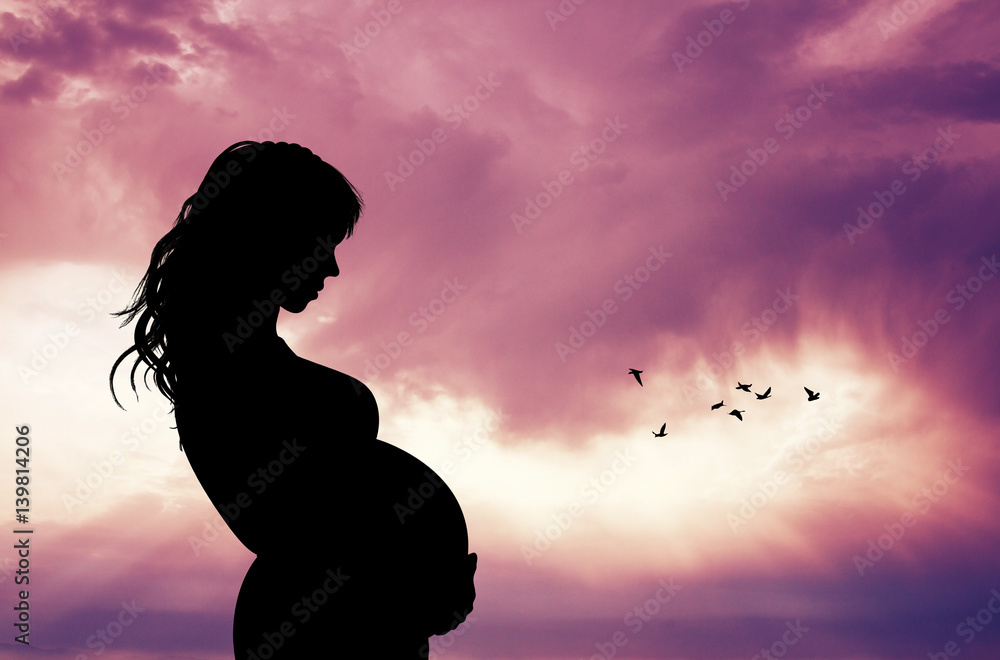 woman expecting a baby at sunset - obrazy, fototapety, plakaty 