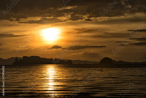 Sunset over the sea at Ao Nang, Krabi, Thailand. Dusk at the beach, orange sky with clouds.