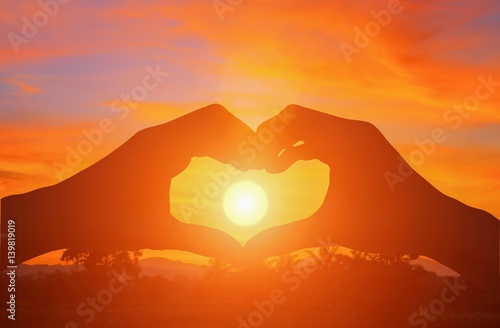 hand forming silhouette a heart shape with sunset light