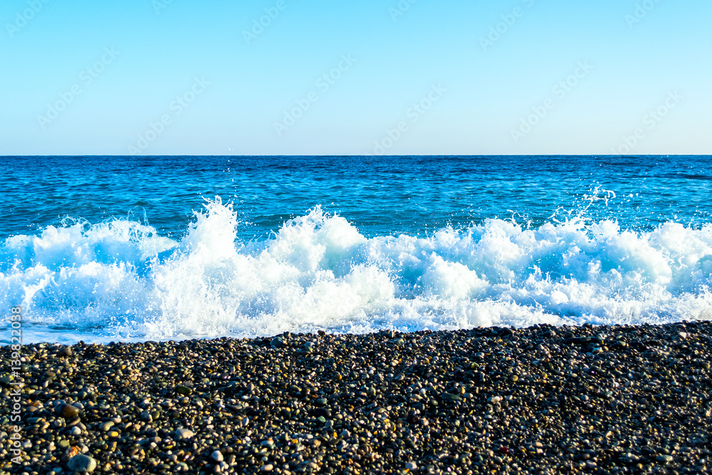 Waves breaking on a stony beach, forming sprays Waves breaking on a stony beach, forming sprays