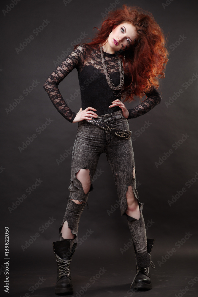 Fashion portrait of a beautiful slim red-haired woman in full growth on a black background.